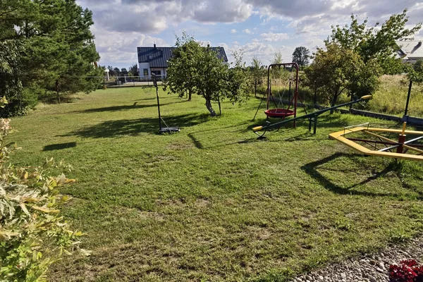 Plac zabaw dla dzieci na terenie U Marianny w Mikoszewie — huśtawki, karuzela i huśtawka wagowa na trawie